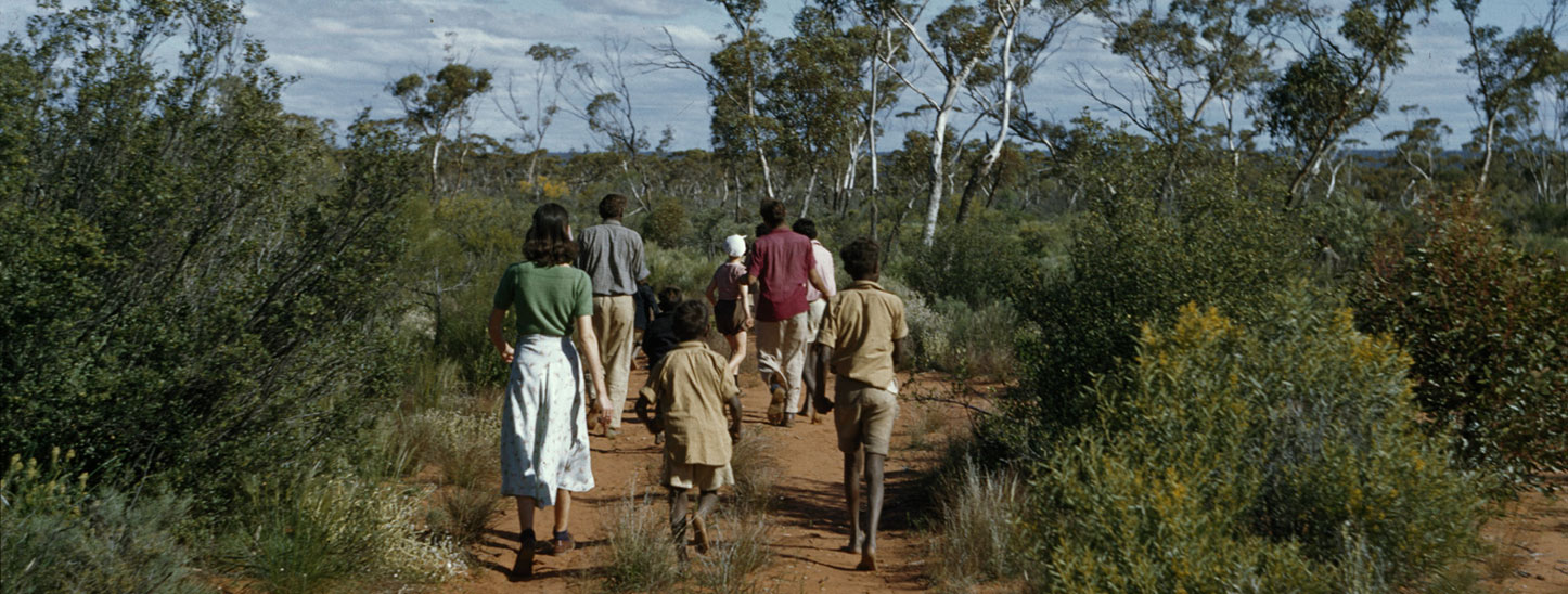 Historical photograph. Aboriginal family group walking on a bush track.