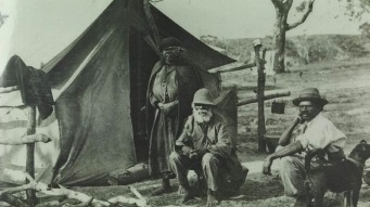 Two Aboriginal men and an Aboriginal women in front of a tent