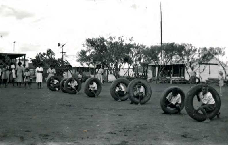 Aboriginal boys in large tyres ready to race