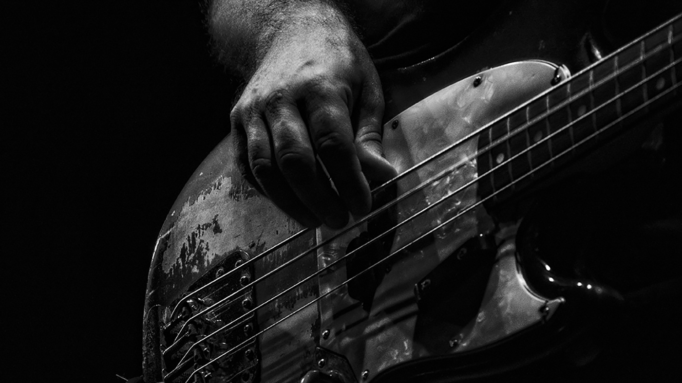 A hand playing an electric bass