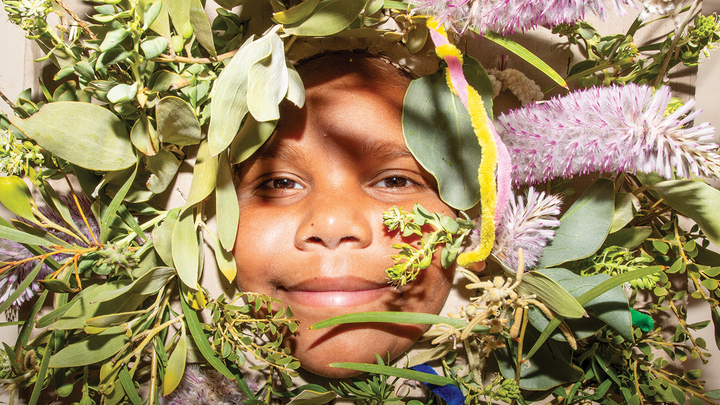 A child's face , surrounded by Australian leaves, flowers and assorted florea.