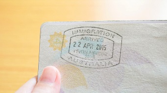 Hand holding passport with Australian immigration stamp for entering the country