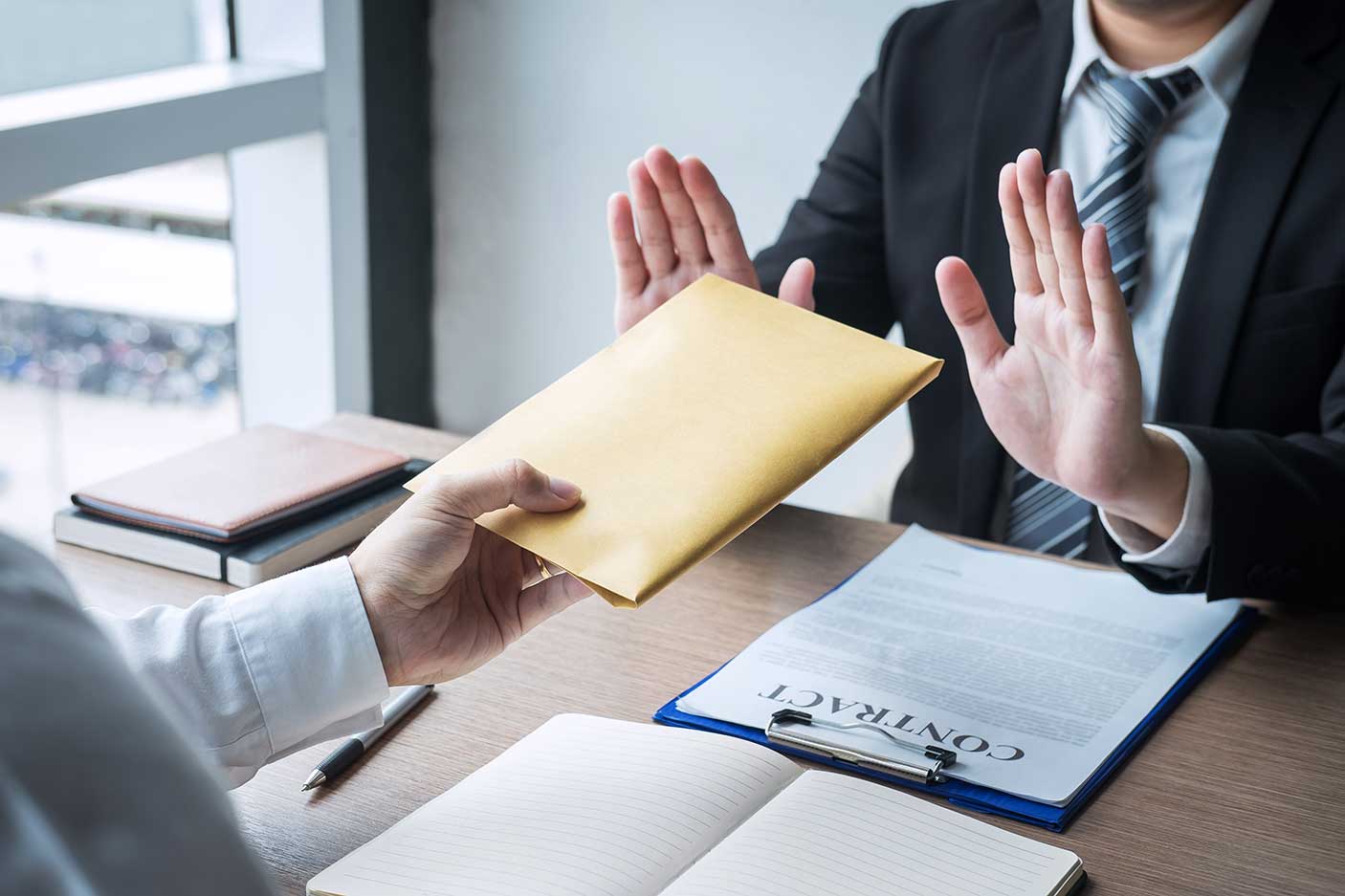 Midsection of business person refusing a bribe on a table