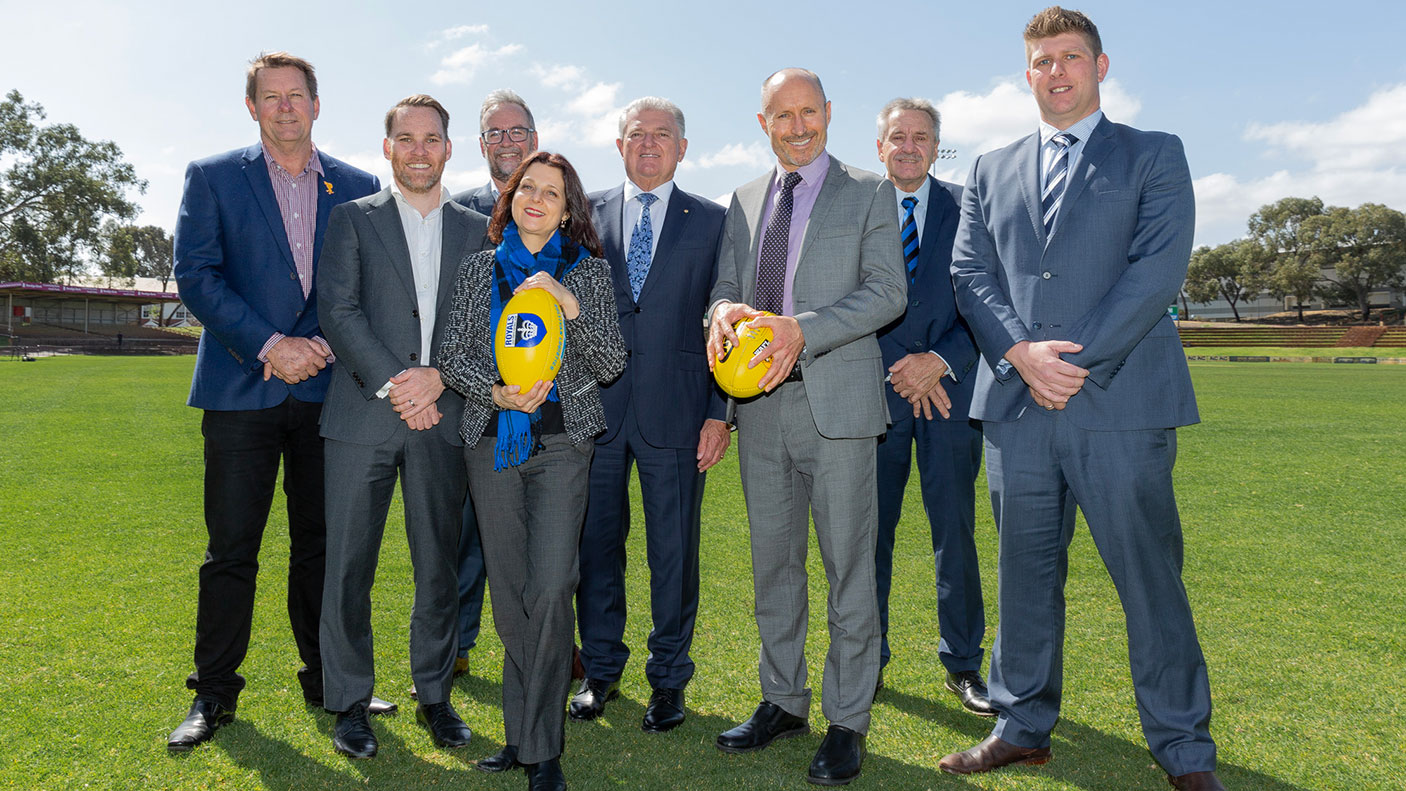 A group of people standing on a football oval, some holding footballs