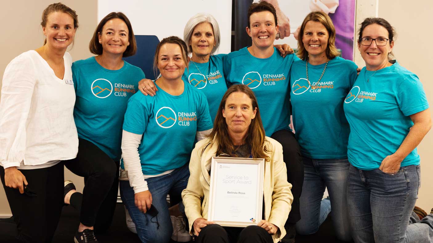 A group of people standing around an award recipient holding a certificate