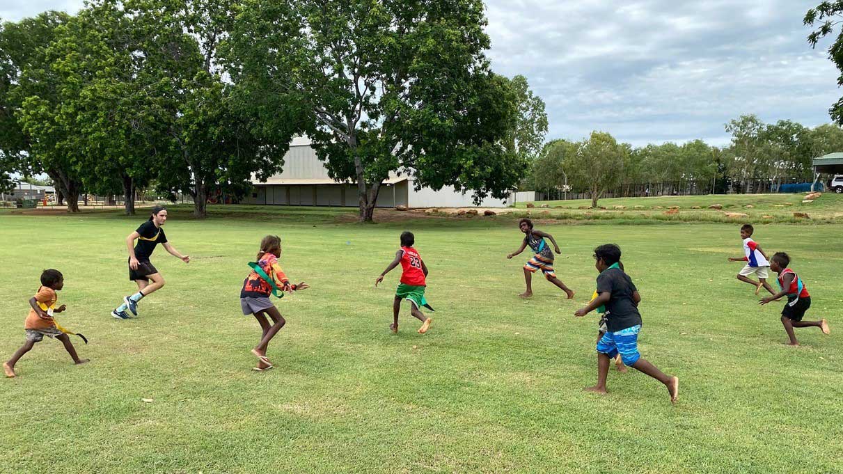 A group of Aboriginal children playing sport on a grass field