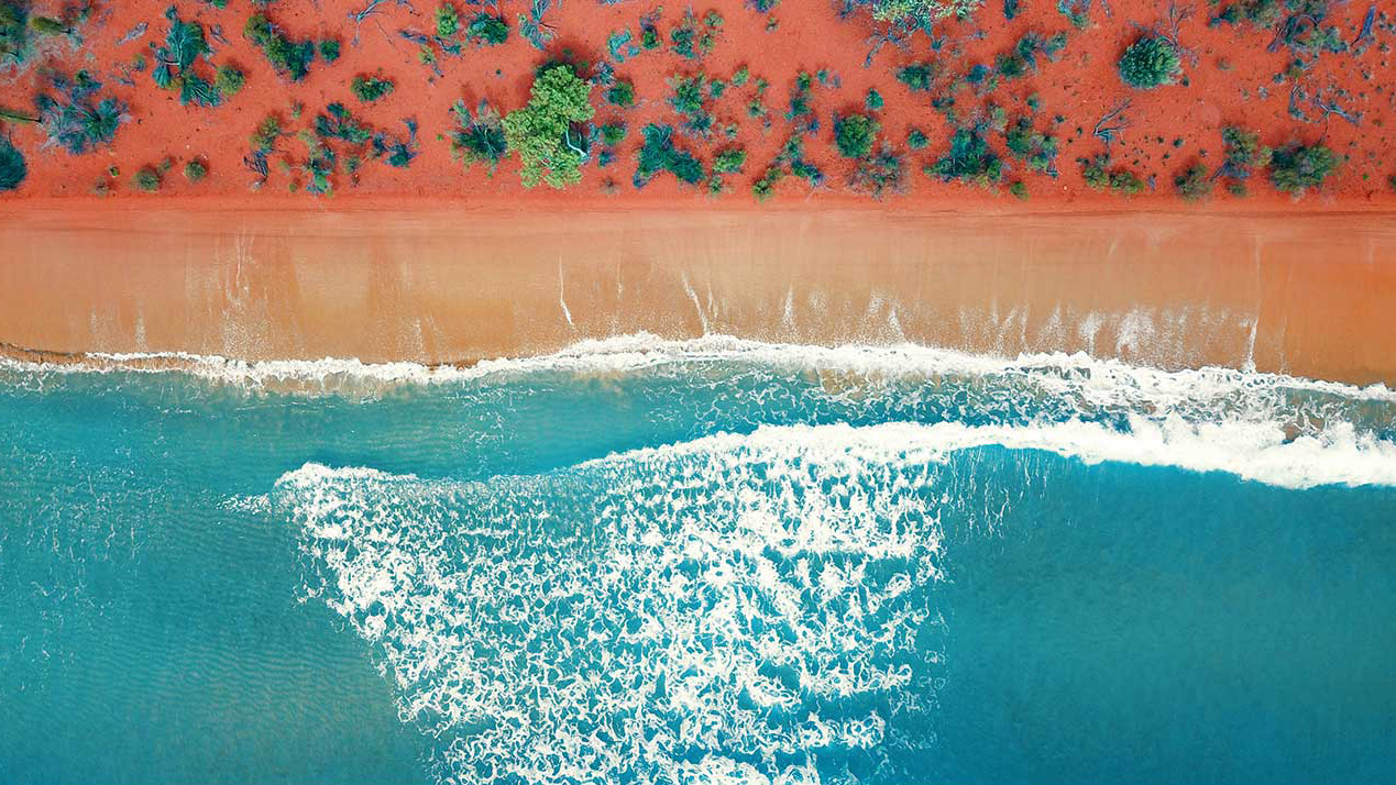 Aerial top view of a bright orange sandy beach