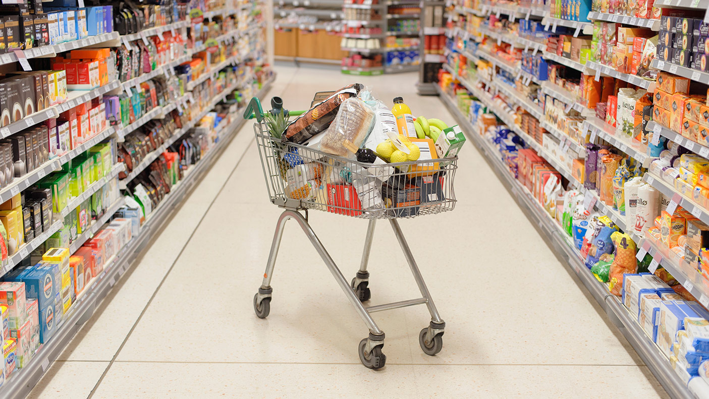 Full shopping cart in supermarket aisle - stock photo