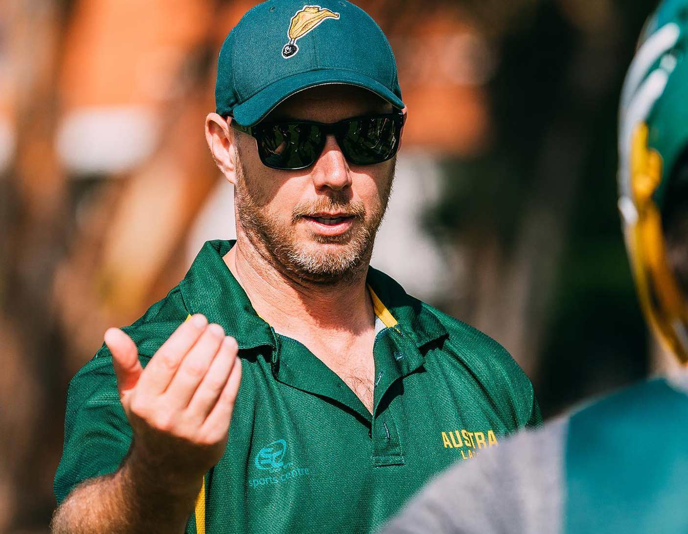 A lacrosse coach gesturing with his hand to a player