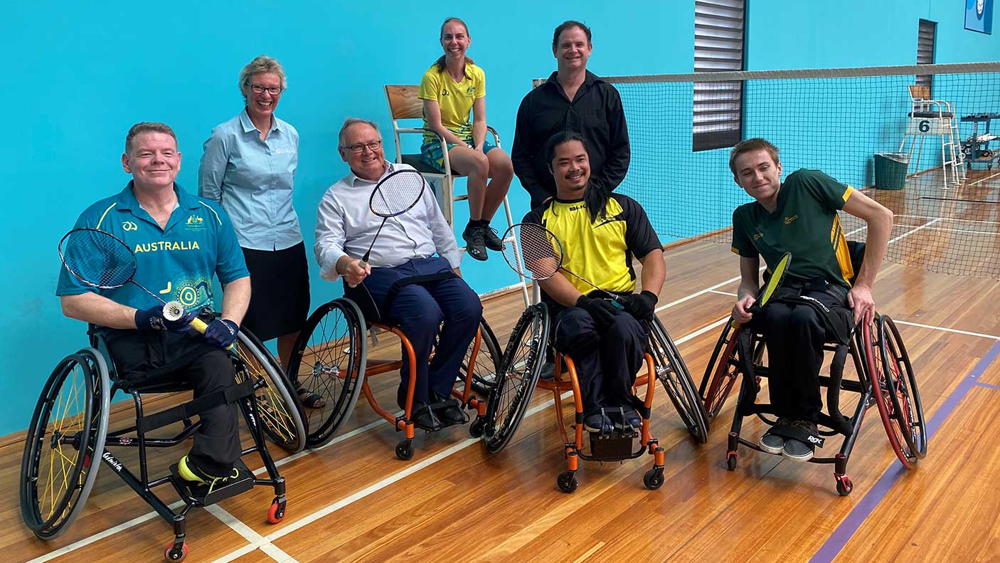 Minister Templeman in a wheelchair with a group of Para badminton players on a badminton court