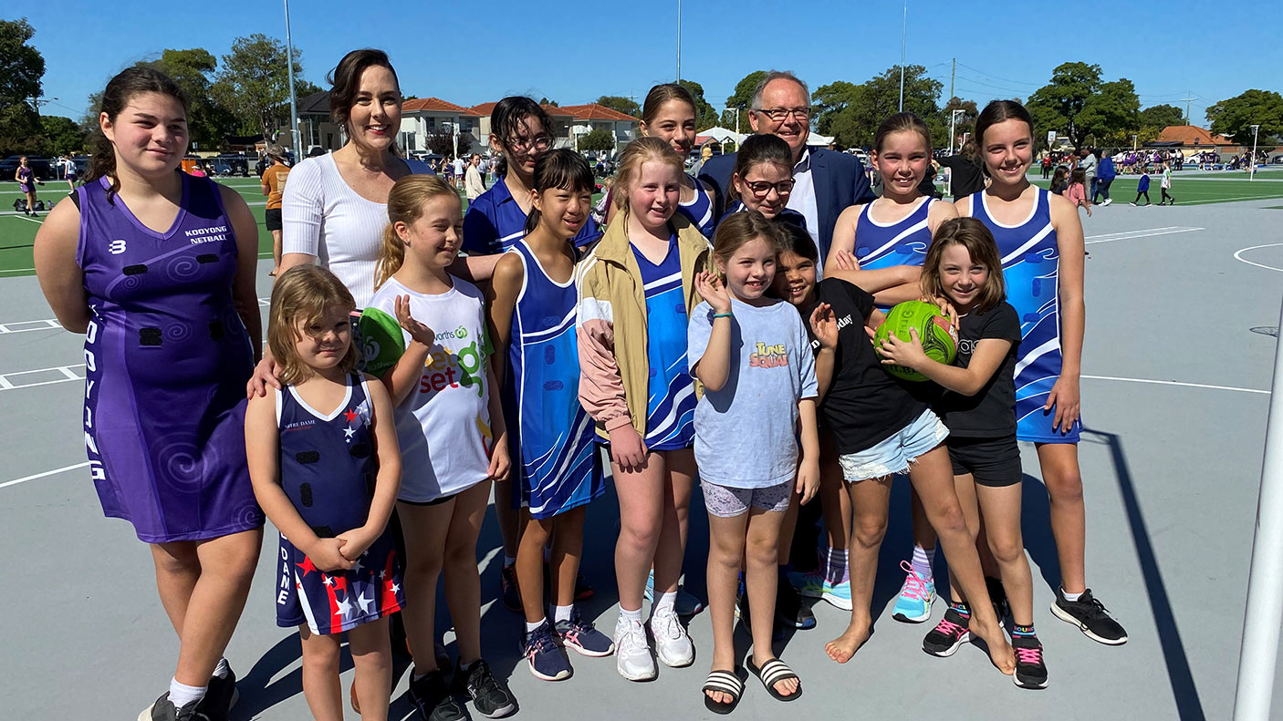 A group of people standing together on a netball court with the Minister.