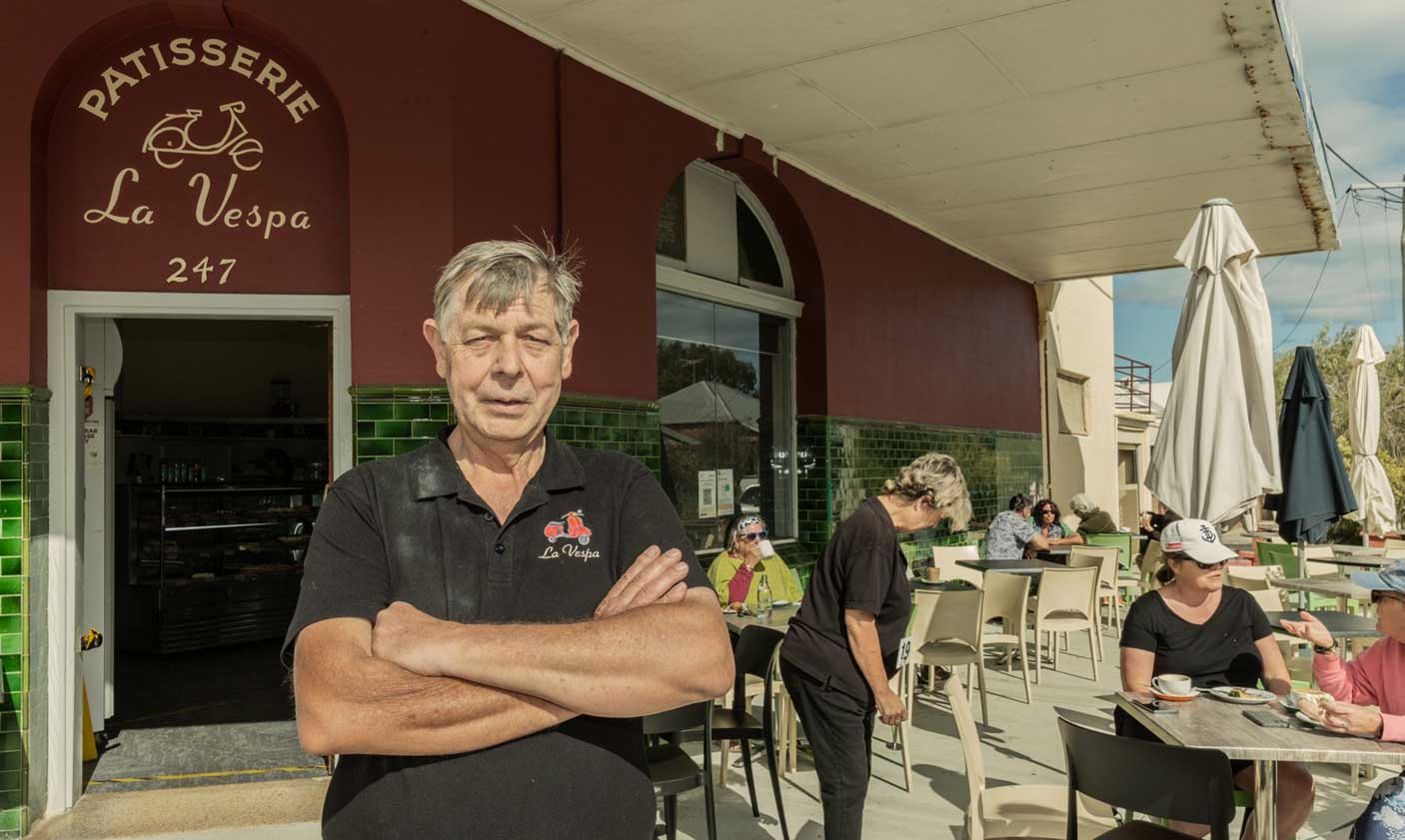 Business owner standing in front of their patisserie with customers using an alfresco area