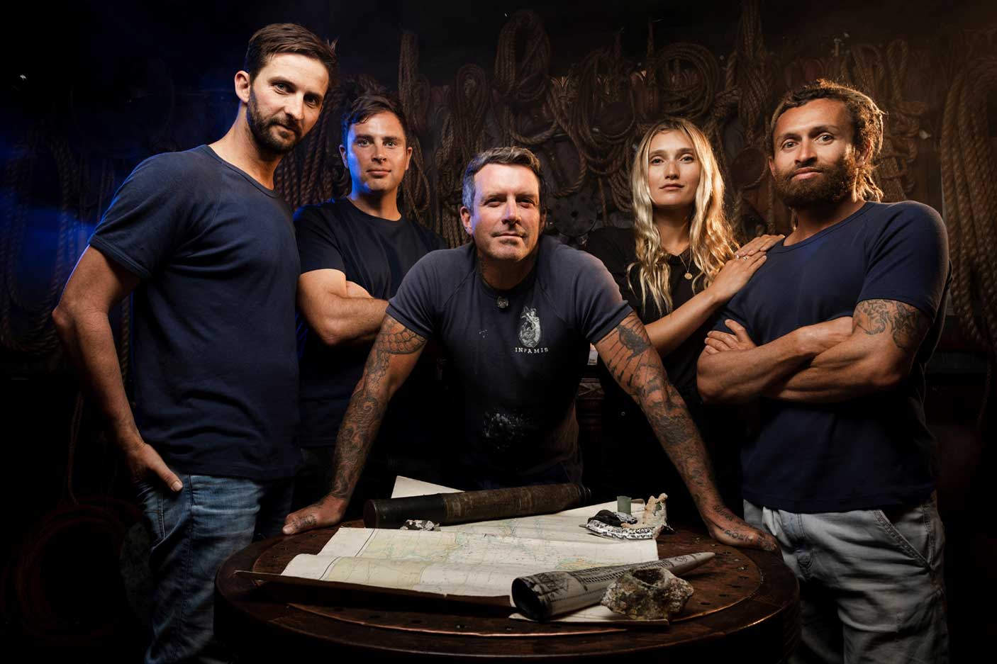 Cast of Shipwreck Hunters Australia standing around a round table with a map