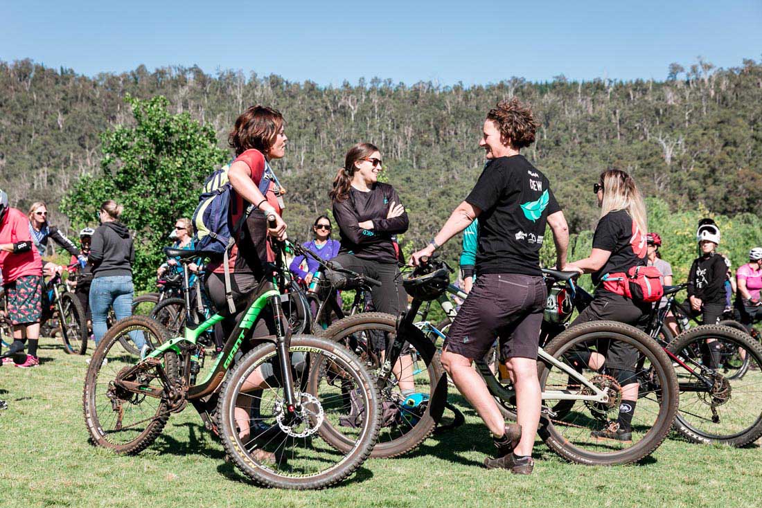 A group of women talking and holding mountain bikes