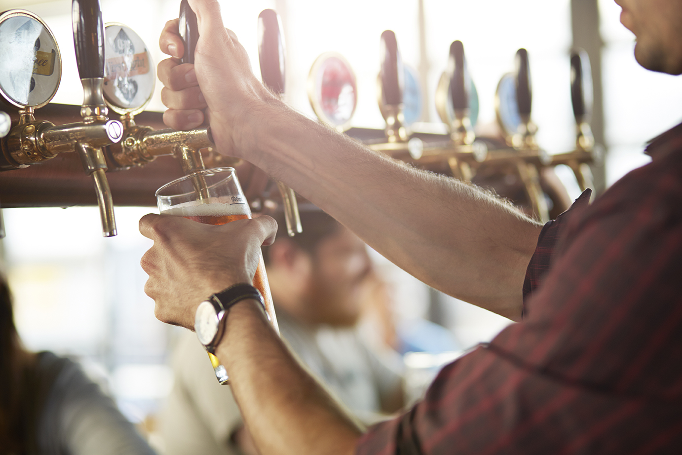 Close up image of a bartender pouring a beer from a tap.