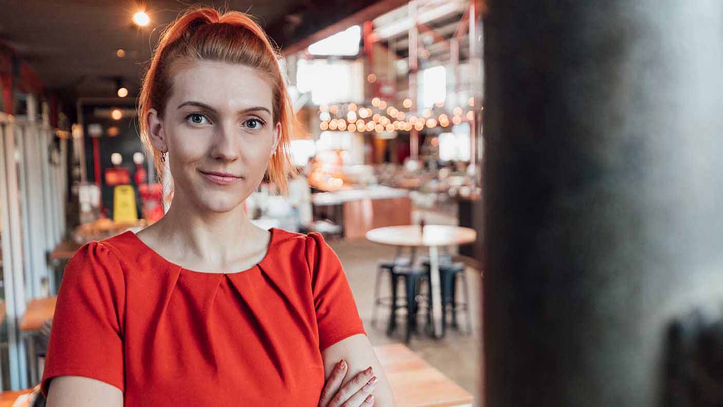 A young female business owner stands for a portrait shot in a food and drink establishment in Perth, Australia.