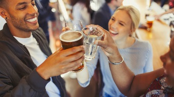 Enthusiastic friends toasting beer and wine glasses at bar