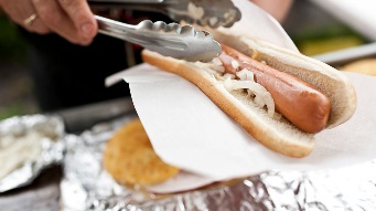 A closeup photograph of someone preparing a sausage sizzle