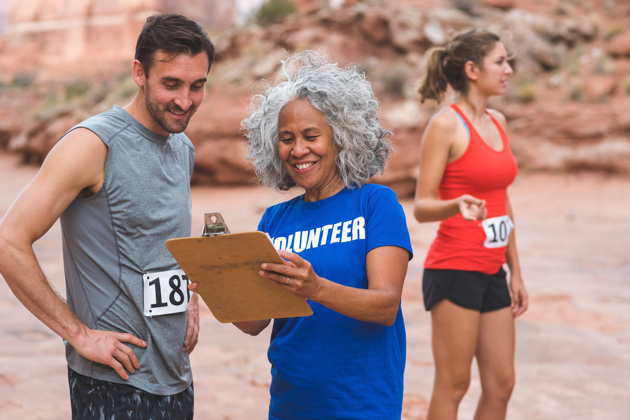 A volunteer with a clipboard interacting with a runner