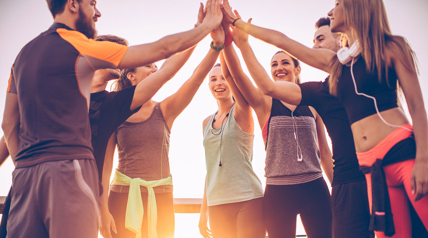 A mixed gender sporting team are high-fiving and smiling